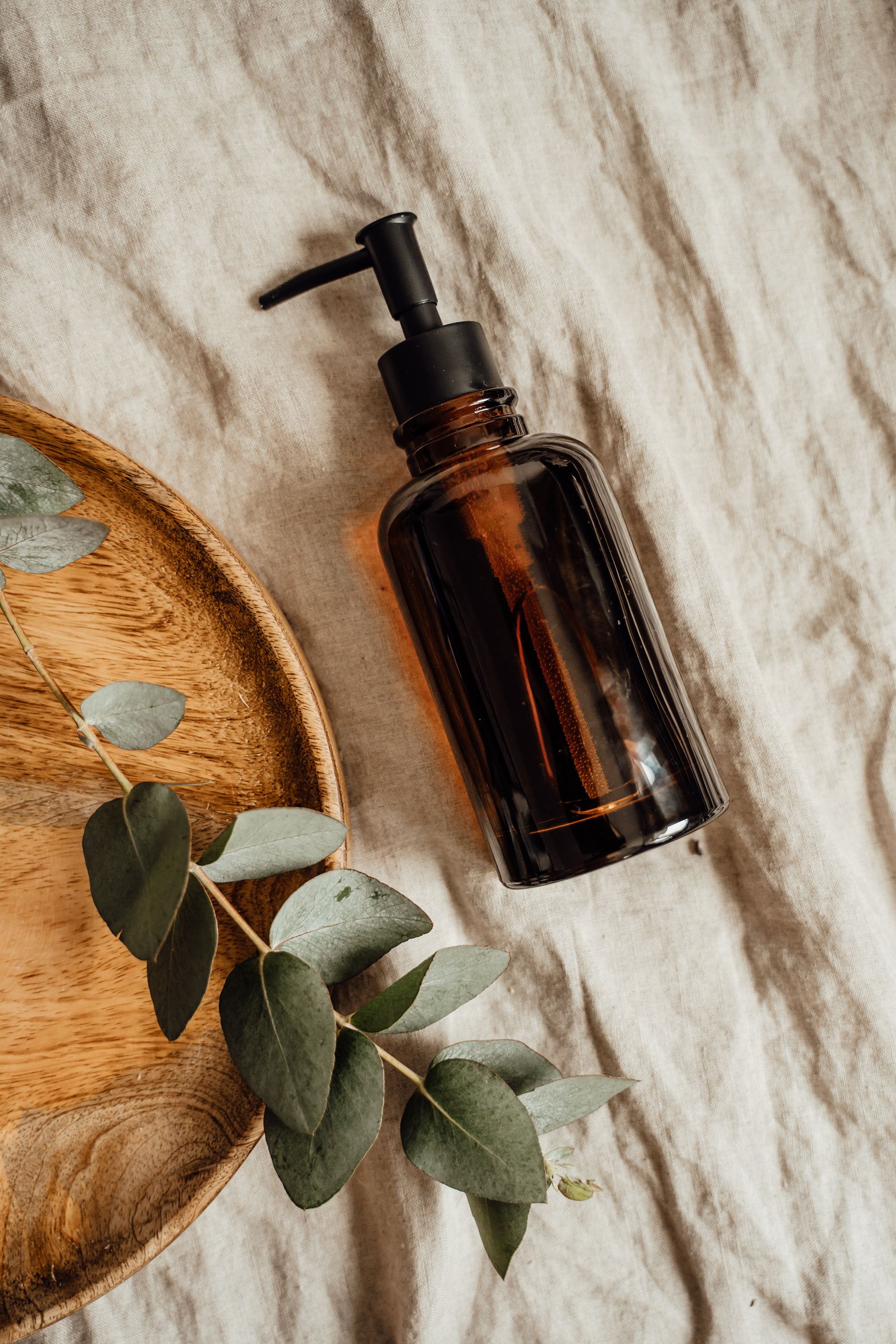 An editorial still life of linen, eucalyptus and unbranded body-care oil